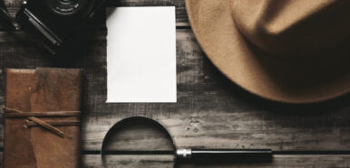 Photo camera, notebook, hat, magnifier, paper on black table